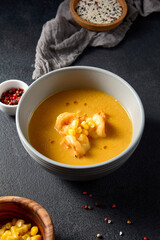 Shrimp and corn curry in a grey bowl with side condiments, a focus on modern Asian cuisine