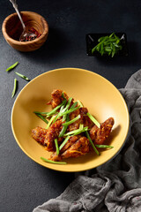 Asian-style buffalo chicken wings on a golden plate with green onions, vibrant and appetizing