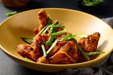 Asian-style buffalo chicken wings on a golden plate with green onions, vibrant and appetizing