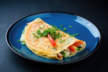 A delicious crepe filled with fresh, colorful sauteed vegetables on a blue plate. Savory Crepe with Sauteed Vegetables