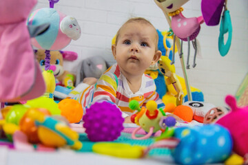 Fototapeta na wymiar a child plays with hanging toys on a play mat. the child plays with toys at home.