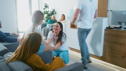 Friendly female doctor or pediatrician is talking to a little girl patient in the waiting room of a medical clinic or hospital. Waiting room in modern medical center. Healthcare system.