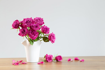 purple roses in vase on white background