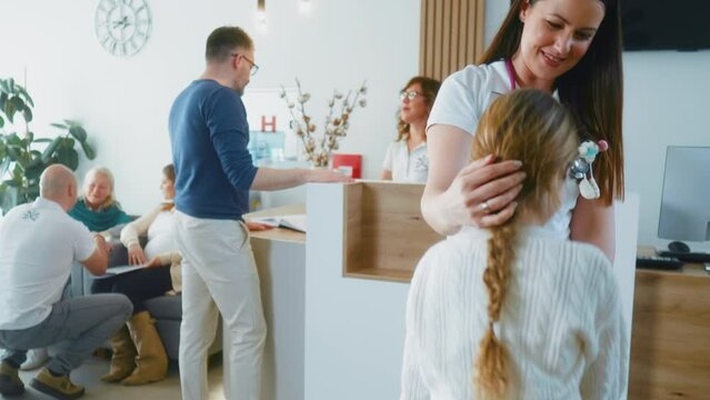Shot of a waiting room with patients and doctors in a modern clinic, a little girl gets up and goes to the pediatrician's examination