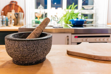 A wooden cutting board sits on a counter next to a mortar and pestle