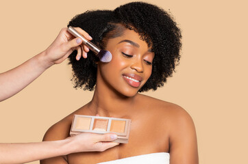 Smiling black woman getting highlighter applied, makeup bliss
