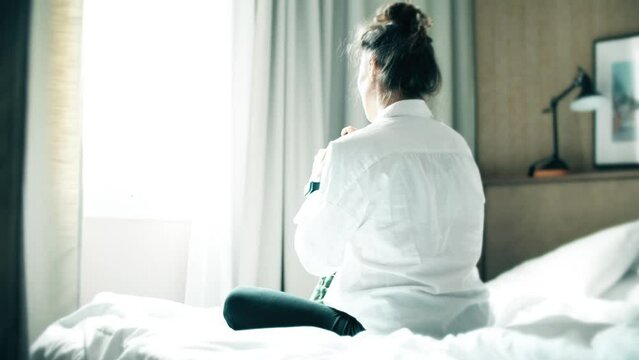 A woman doing her makeup on the bed in the hotel room