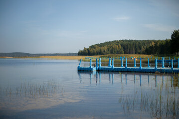pier for boats on an autumn lake, early autumn, rest and relaxation in the first autumn days, blue...