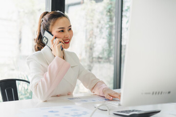 Portrait of beautiful asian secretary woman working with cellphone and desktop in office.