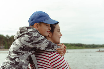 Family Bonding: Son Hugging Mother in Affectionate Embrace at Lake Camping Trip