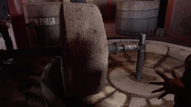 Person explaining the use of a stone wheel in the artisanal production of mezcal or tequila.