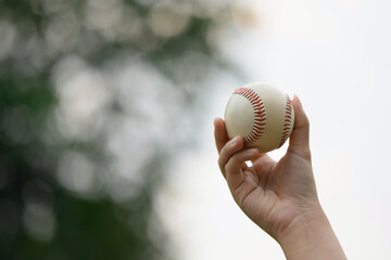 Closeup hand holding a baseball on the sports field. Fitness, sports and training concept