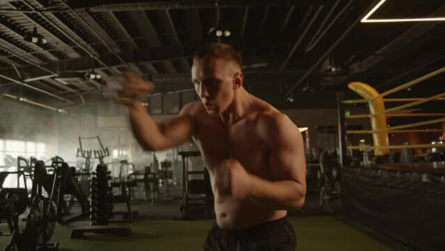 professional young muscular man is practicing shadow boxing work out in a ring. 