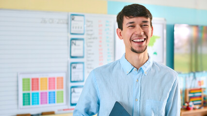 Portrait Of Male Primary Or Elementary School Teacher Holding Digital Tablet Standing In Classroom - 763130588