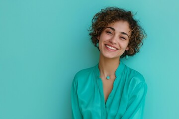 Portrait of a cheerful woman with short curly hair on a turquoise color background looking at camera.