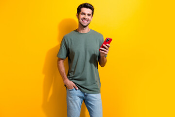 Photo of clever smart man with bristle dressed khaki t-shirt hold smartphone keep hand in pocket...