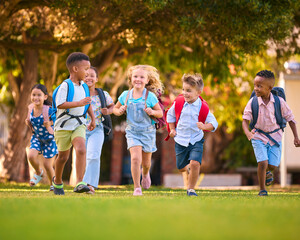 Multi-Cultural Primary Or Elementary School Students With Backpacks Running Outdoors At End Of Day