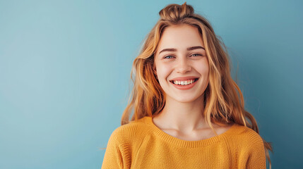 Pretty smiling joyfully female with fair hair, dressed casually, looking with satisfaction at camera, being happy on pastel blue background - obrazy, fototapety, plakaty