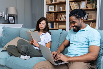 Simple living. Young couple man and woman at home working on laptop, reading book, talking and argue, making fun. Real life situations of two people living together with support and issues