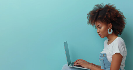 Laptop in hands of happy 35 years black woman freelancer wearing white t-shirt, sitting on blue background. Concept of freelance, studying, IT technology, cyberspace