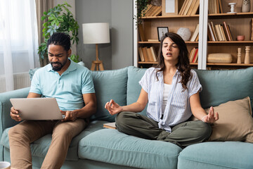 Simple living. Young couple man and woman at home working on laptop, reading book, talking and...