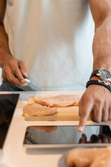 Black man looking on the digital recipe, using touchscreen tablet while cooking healthy meal on the kitchen at home, close-up view