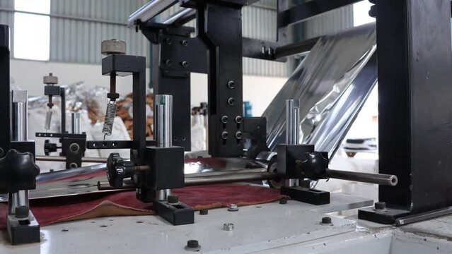 Bangalore, India 1st February 2024: Modern factory for the production of Silver Foil Bags. Roll of aluminum foil for food packaging on automatic packing machine. Food Grade quality pouches for Hotels.