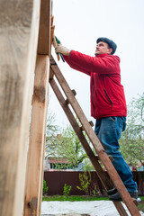 A worker builds a roof in a house while standing on a wooden ladder