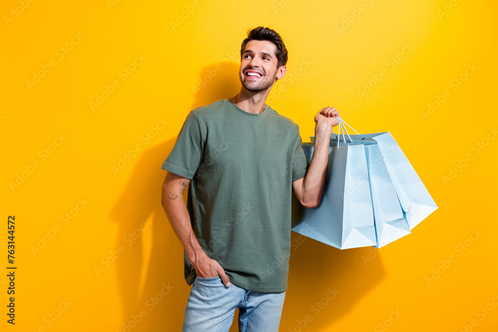 Poster photo of optimistic man dressed khaki t-shirt hold new clothes look at proposition empty space isola