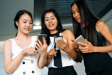 Three women friends having conversation while looking at mobile phone in their hands. Concept of...