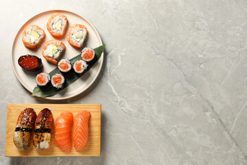 Delicious sushi rolls on light grey marble table, flat lay. Space for text