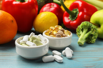Dietary supplements. Bowls with different pills near food products on light blue wooden table, closeup