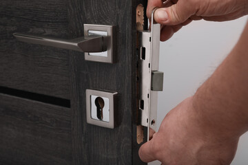 Handyman changing door handleset indoors, closeup view