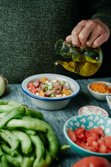 man dressing a broad bean salad with olive oil - 763156746