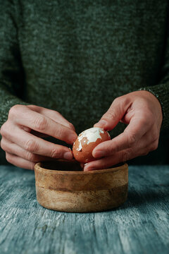 man peeling a brown boiled egg