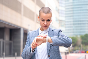  portrait of a serious business woman looking at the time on the clock outdoors.