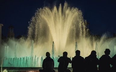 A crowd of people watches evening show of Magic Fountain in Barcelona, Spain