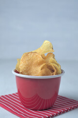 Potato chips in red bowl with red napkin isolated on white.