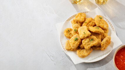 Delicious golden chicken nuggets on a plate on the table. Fast food, menu. Copy space