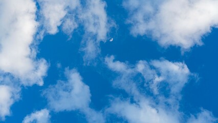 Beautiful vivid blue sky with white clouds and moon in background
