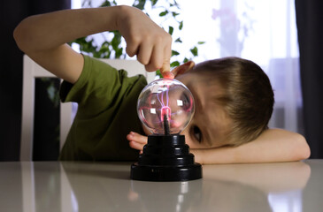 Hands holding plasma light ball. Science of light rays. Child studies touching glass sphere with...