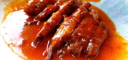 Delicious dish of duck in sauce. Peking duck. Duck in Thai. An appetizing dish of duck or chicken. Sliced ​​meat in red sauce close-up. Restaurant dish.