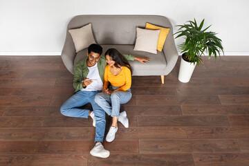 Hindu spouses engaging in phone at home, above view, copy space