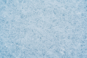 Close-up photo of transparent light blue ice of Baikal lake with white frost ornament. Great...