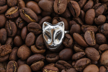 Top view on silver ring on a background of coffee beans. Handcraft precious item. Jewelry accessories.