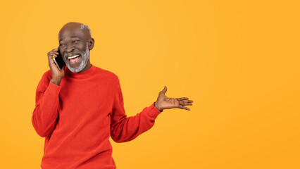 Happy senior black man in red sweater talking on the phone with a delighted expression