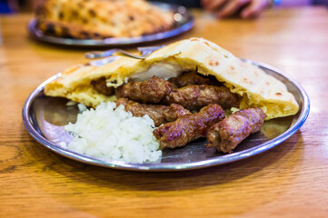 Traditional bosnian barbecue dish cevapi served with somun and chopped onions. Famous balkan BBQ...