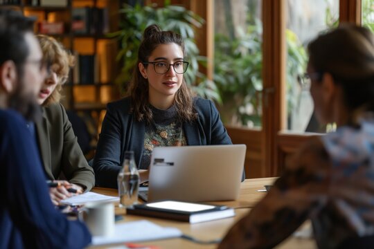Casual business discussion in cozy office. Woman in glasses discussing work with colleagues in a casual office setting