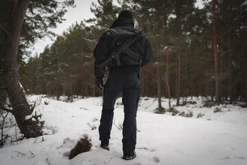 A private military warrior man with an AK 12 rifle behind his back in a winter forest, photo from...