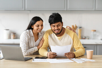Cheerful indian spouses paying bills on Internet from home